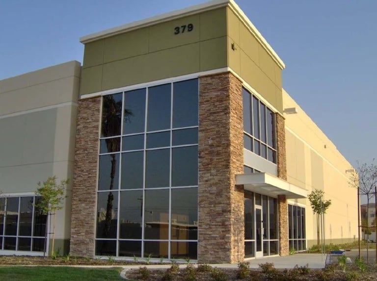 Modern commercial building with yellow exterior, brick accents, large windows, and unit number 379 on top